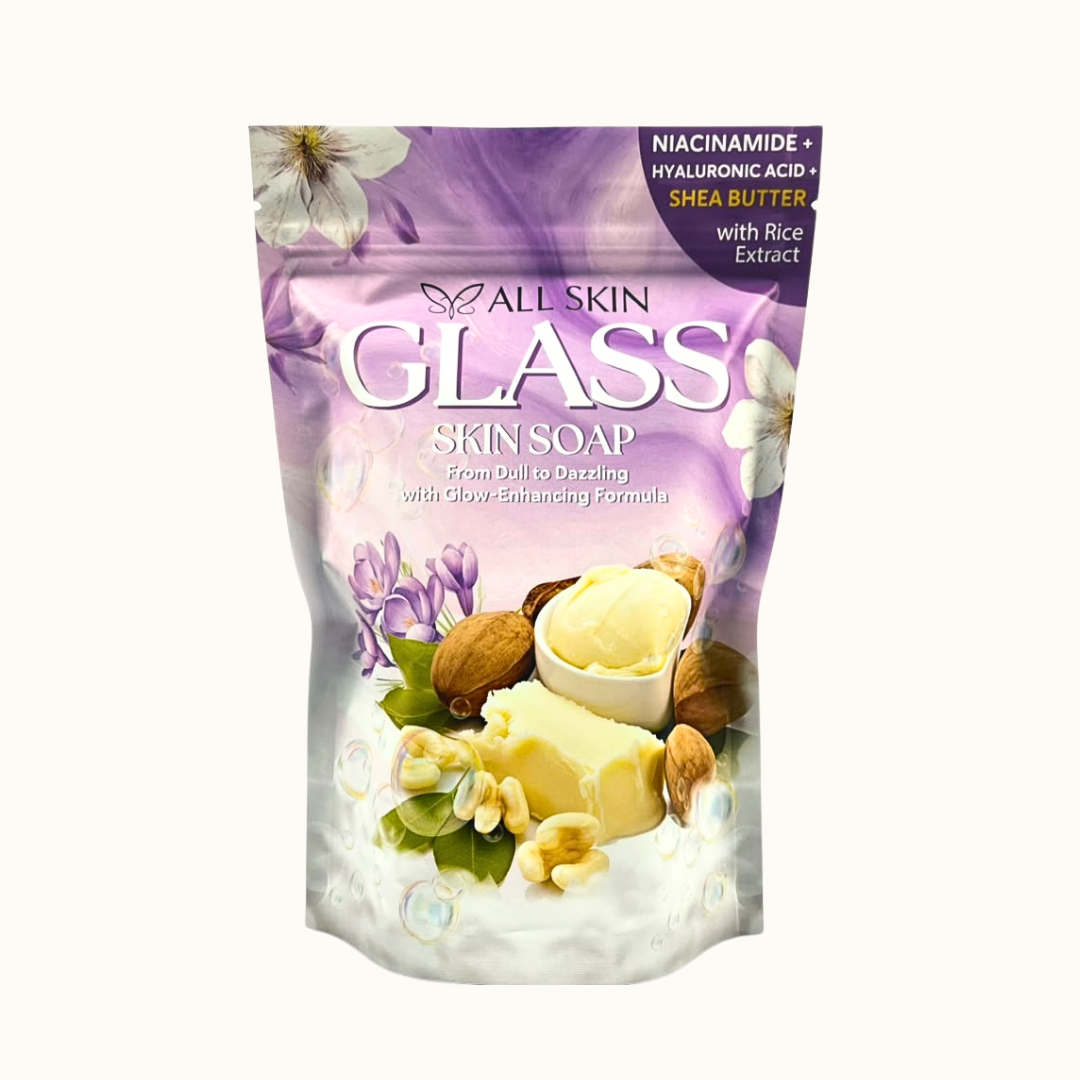 A stand-up pouch of All Skin Glass Skin Soap on a plain off-white background. The packaging is primarily purple and white with illustrations of flowers, nuts, and a bar of soap, and text highlighting niacinamide, hyaluronic acid, shea butter, and rice extract.