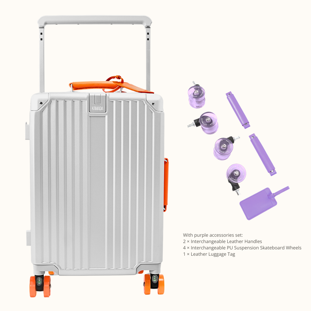 A silver aluminum hard-shell suitcase with orange accents and a telescoping handle, shown alongside purple accessories including two leather handles, four PS suspension skateboard wheels, and a luggage tag on a light beige background.